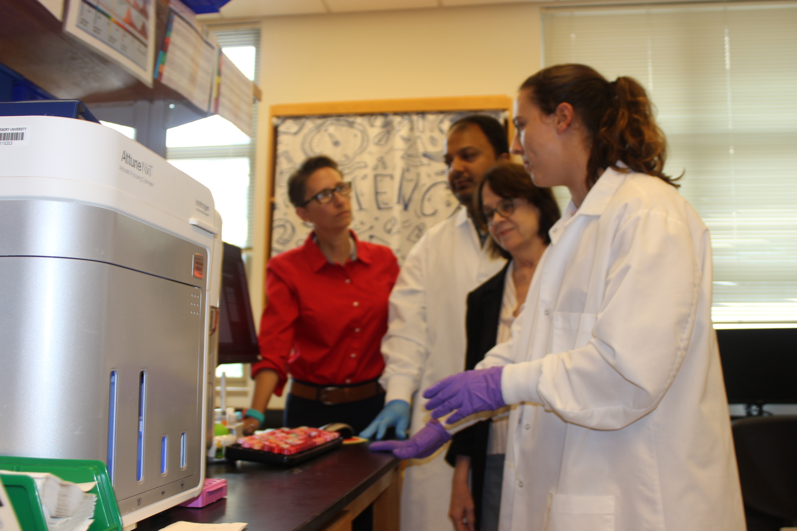 Researchers in a lab discussing samples beside scientific equipment.