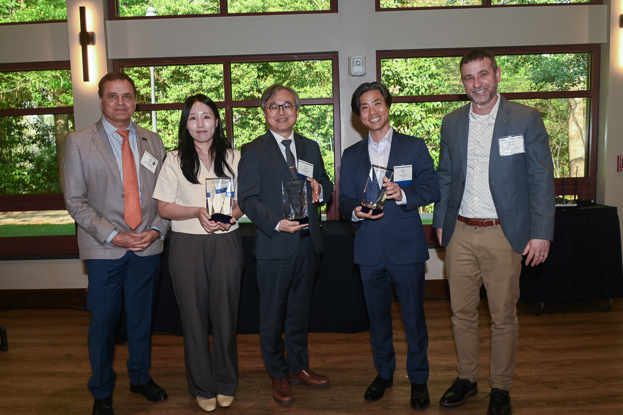Group of five poses indoors holding glass awards after a ceremony.
