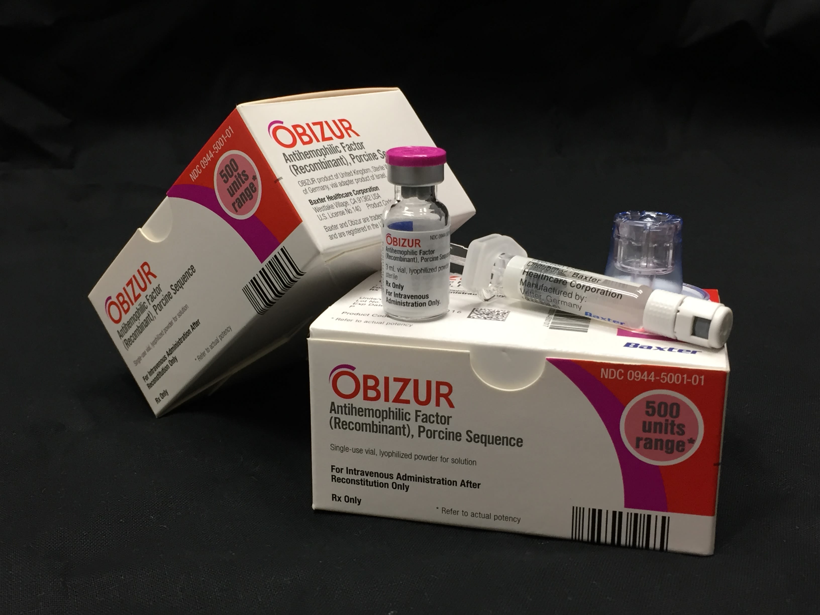 Two boxes of Obizur with a glass vial and needle sitting atop one of them