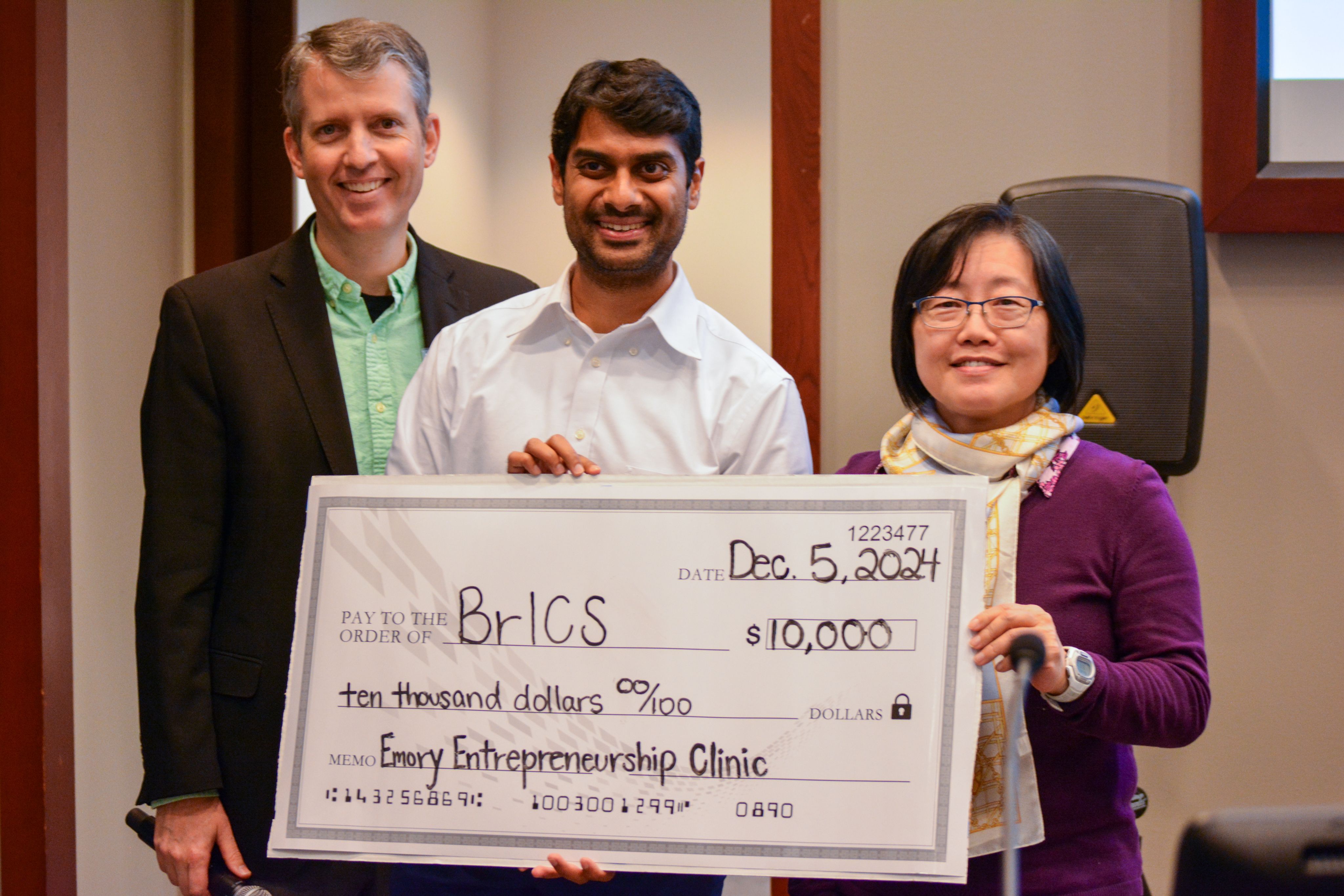 Photo of Karthik Ramesh and Hyunsuk Shim holding a large check, with EEC coordinator Patrick Reynolds on the left