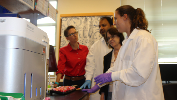 Researchers in a lab discussing samples beside scientific equipment.