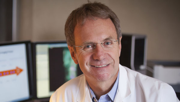 Doctor sitting at a desk with computers in the background